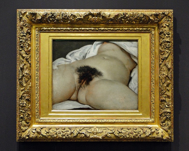 It is a close-up view of the genitals and abdomen of a naked woman, lying on a bed with legs spread. The framing of the nude body, with head, arms and lower legs outside of view, emphasizes the eroticism of the work.